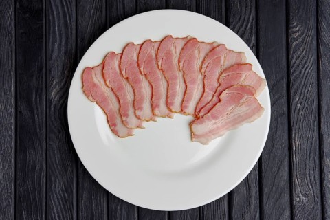 Top view of plate with slices of fresh bacon