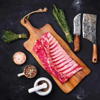 Fresh raw rack of lamb on wooden cutting board with herbs and seasoning