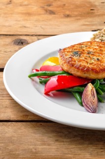 Close up view of salmon cutlet with roasted vegetables and green buckwheat