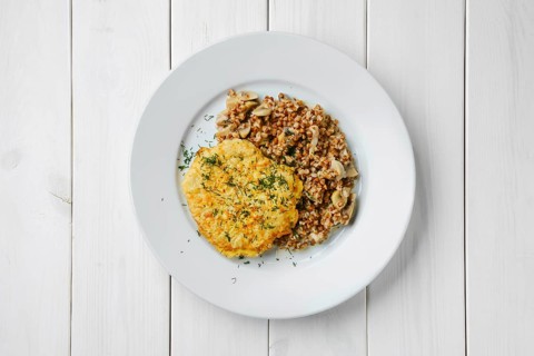 Top view of chicken cutlet in breading with buckwheat and mushrooms