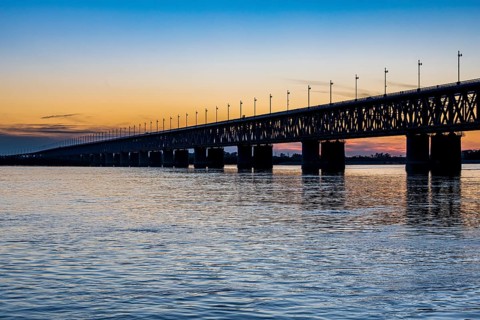 Giant bridge spanning over the Amur river at sunset