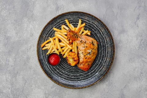 Top view of baked chicken thigh with french fries
