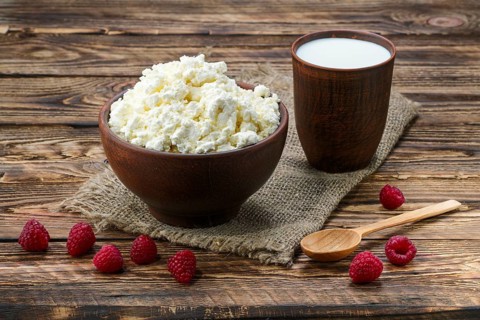 Cottage cheese and milk in clayware on wooden table