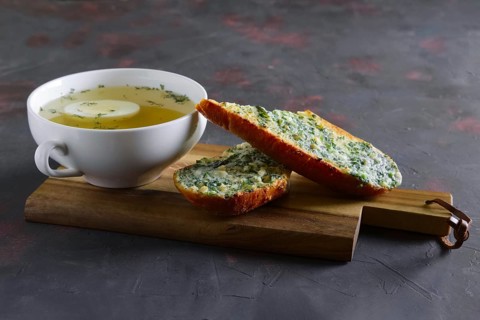 Clear chicken broth with egg served with toasts