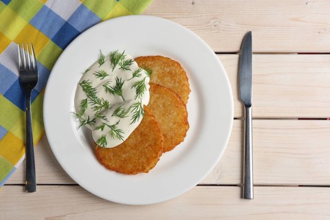 Draniki with sour cream on wooden table