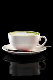 Cup of green tea latte isolated on black background