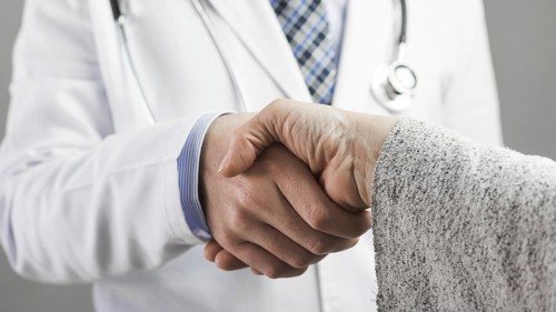 Close up male doctor patient shaking hands