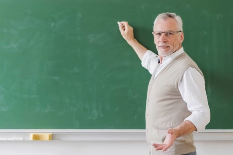 Senior male professor explaining writing green chalkboard