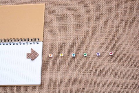 Love cubes and paper arrow on a notebook on canvas