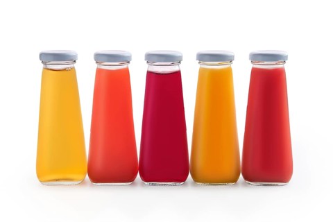 Assorted juices in small glass bottles isolated on white background