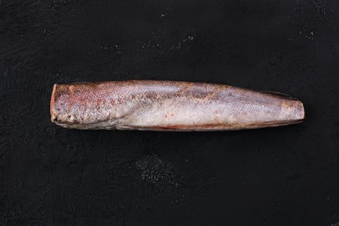 Raw frozen hake on black background