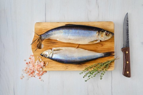 Overhead view of fresh whole carcass of herring on wooden cutting board
