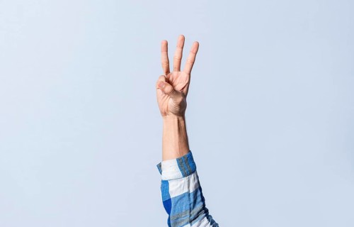 Hand gesturing the letter W in sign language on an isolated background. Man's hand gesturing the letter W of the alphabet isolated. Letter W of the alphabet in sign language