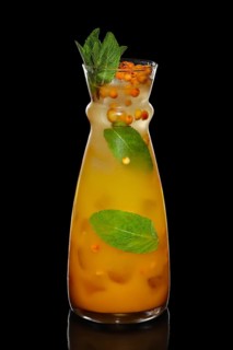 Decanter with sea buckthorn and mint lemonade isolated on black
