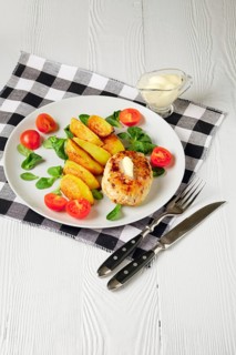 Fried chicken cutlet with potato slices served with tomato cherry and corn salad. Traditional belorussian food