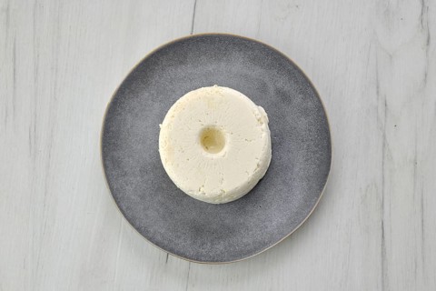 Top view of pressed cottage curd cheese on ceramic plate