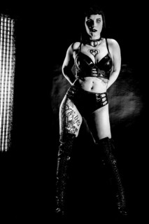 Woman with black hair and tatoos in vinyl and latex outfit