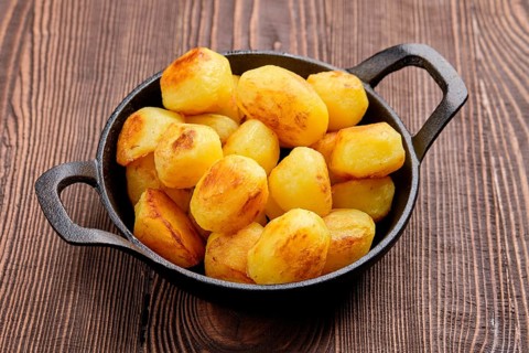 Baked potato in cast iron skillet on natural wooden background