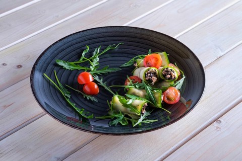 Chopped smoked salmon and black olives rolled in cucumber decorated with tomato and arugula