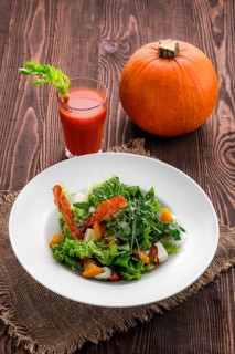 Salad with feta and bacon with tomato juice and pumpkin on wooden table