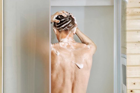 Back view of a man washing hair in the shower