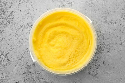 Top view of homemade cream cheese in plastic bowl