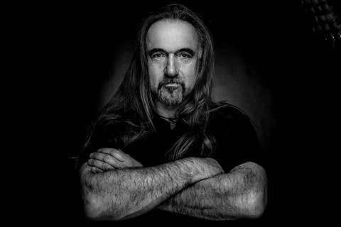 Man with long hair and hand with folded arms