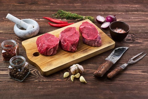 Marinated raw beef steak with spice on wooden table