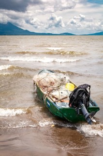 A fishing boat on the shore of a lake with volcanoes in the background. A fishing boat on a lake in Nicaragua. Concept of fishing boats parked at the seaside