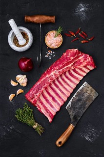 Fresh raw rack of lamb on wooden cutting board with herbs and seasoning