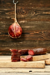 Smoked dried deer sausage cut on slices on wooden cutting board