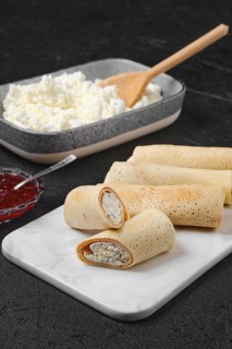 Homemade pancakes stuffed with cottage cheese on marble serving plate