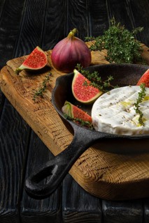 Closeup view of camembert cheese and figs ready for baking on frying pan