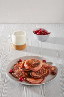 Pancakes with cherry and glass of milk on white kitchen table