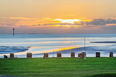 Grassy beach with beach chairs at sunset on the Wadden Sea at the mouth of the Weser