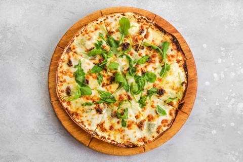 Top view of thin-crust pizza dough with walnuts