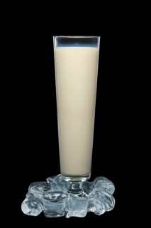 Tall glass of milk surrounded with ice cubes isolated on black background