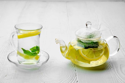 Antioxidant hot drink with lemon and mint in transparent tea pot and glass