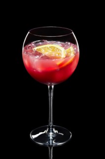 Cold lemon cocktail with a sparkling wine and raspberries with ice in wine glass isolated on black