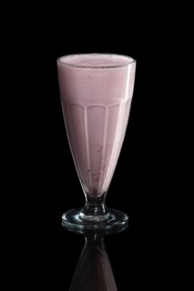 Glass of raspberry milk cocktail isolated on black