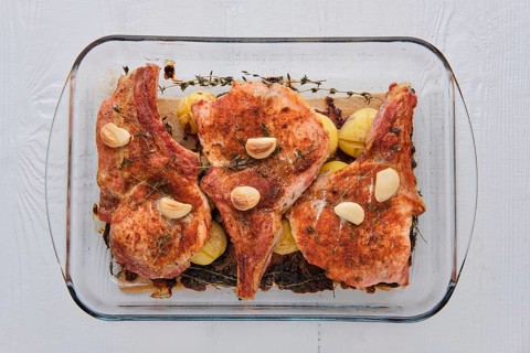 Steak with bone and potato baked in oven in a roasting pan with garlic and thyme