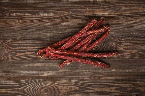 Overhead view of air dried deer and pork sausage on wooden background