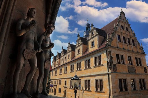 The figures of Adam and Eve on the main portal of the church of St. Moritz and the building of the Casimirianum grammar school