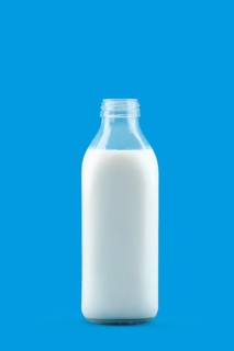 Open bottle of milk isolated on blue background