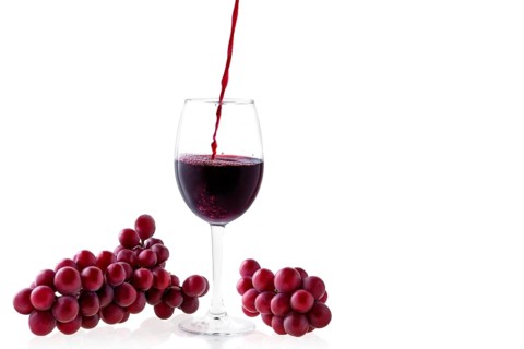 Pouring red wine in glass isolated on white background