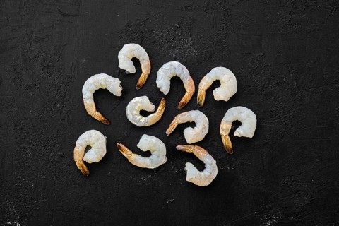 Peeled fresh raw white prawns on wooden background