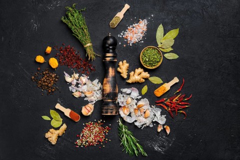 Assortment of spice and seasonings scattered on dark background