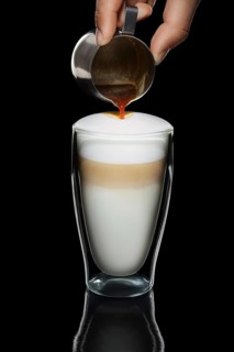 Hand with pitcher making pattern on cappiccino topping