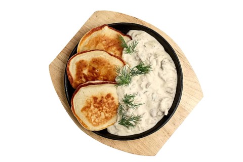 Flapjack with mushroom sauce on wooden plate. Top view