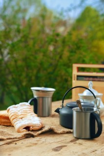 Camping kettle with a mug and biscuit on the table outdoors